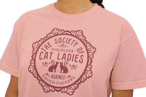 The Society of Childless Cat Ladies Against Couch Fuckers" 2024 election T Shrort design featuring two cats in an ornate circular frame, available in white and purple.